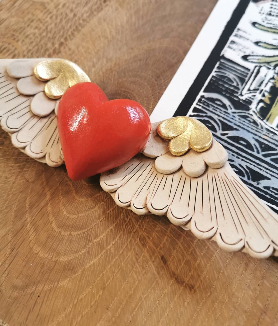 Ceramic winged heart wall art with red glazed heart and gold feathers