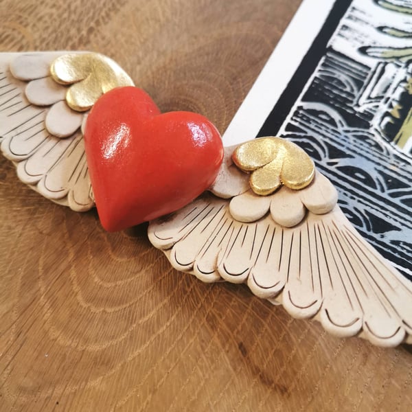 Ceramic winged heart wall art with red glazed heart and gold feathers