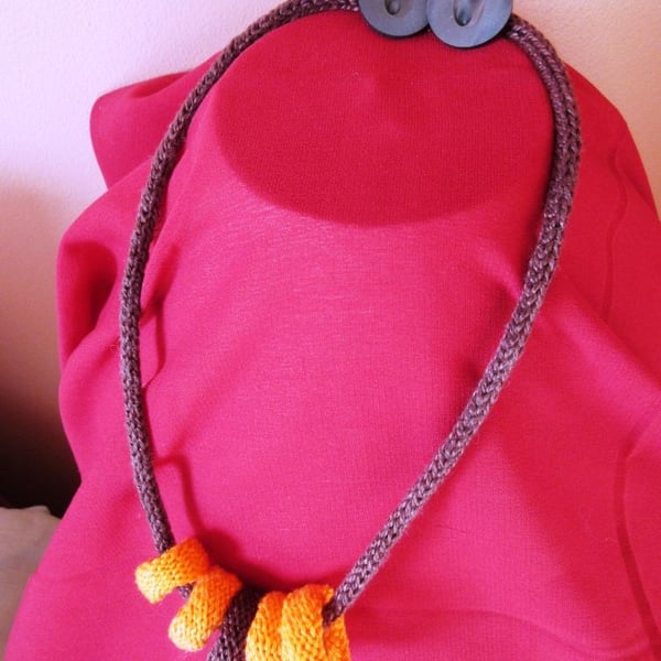 A knitted necklace of 5 knitted rings threaded on a cord of French knitting 