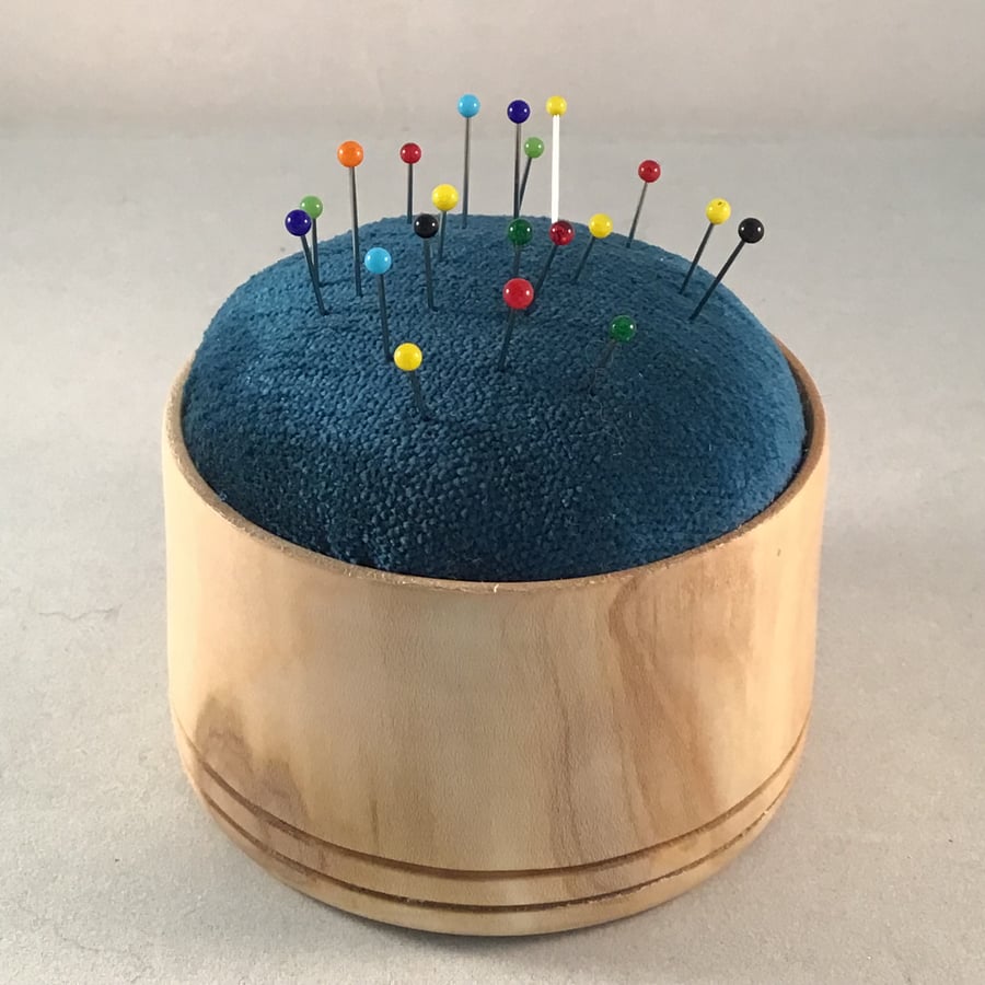 Natural wood encased pin cushion.