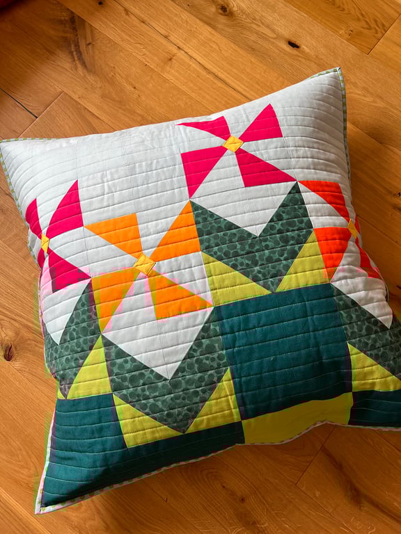 Pink & orange geometric flowers on a quilted floor cushion