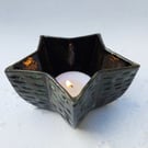 Votive in black clay, with carved texture - star