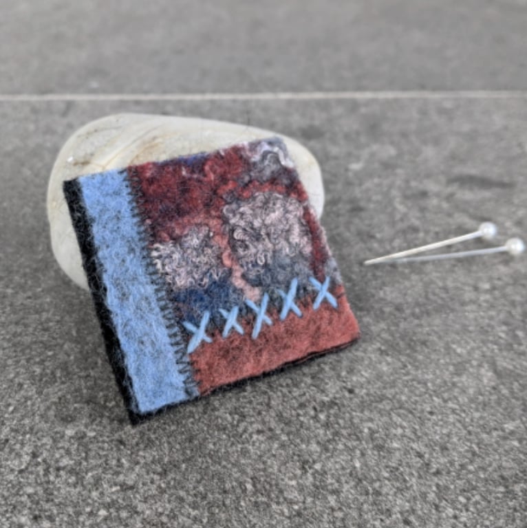 Felted patchwork brooch in shades of pale blue and rusty orange.