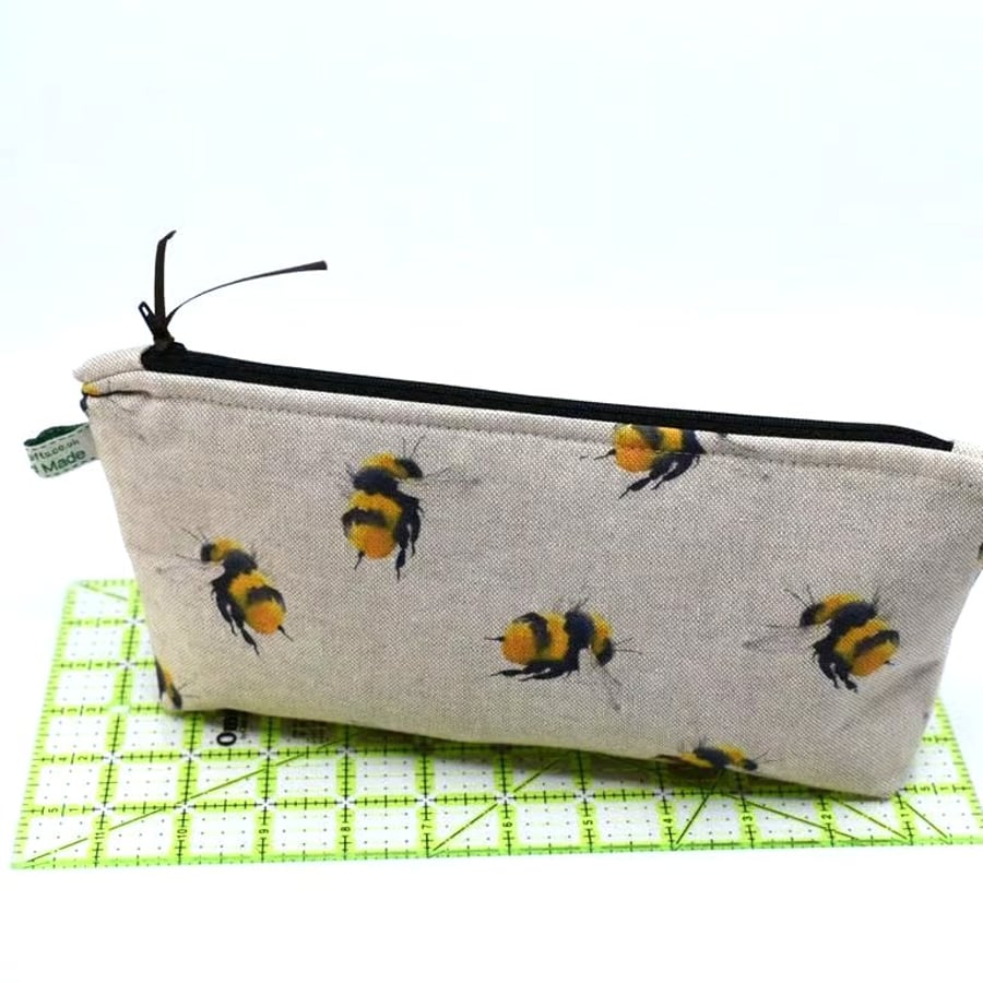 A zipped pouch, bumble bee print on linen style cotton. Many use home or away.