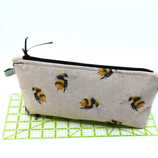 A zipped pouch, bumble bee print on linen style cotton. Many use home or away.