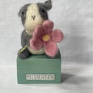 Handcrafted needle felted rabbit holding a flower on a wooden box
