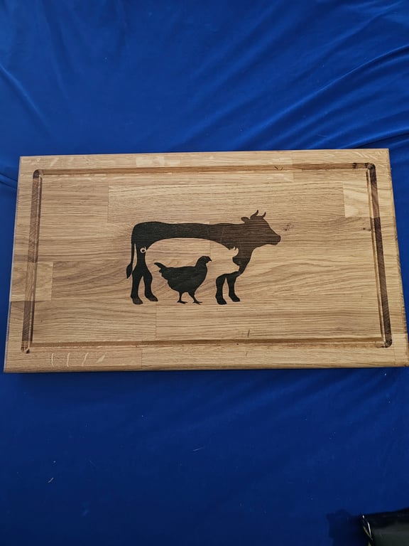 Solid oak chopping board with cow, pig and chicken detail.