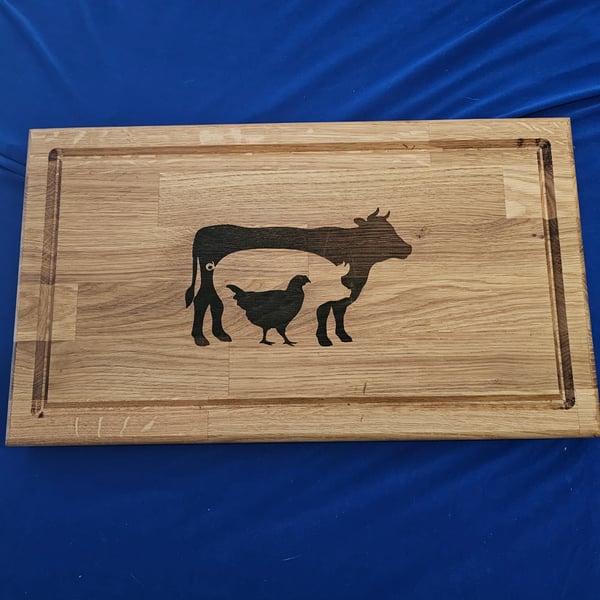 Solid oak chopping board with cow, pig and chicken detail.