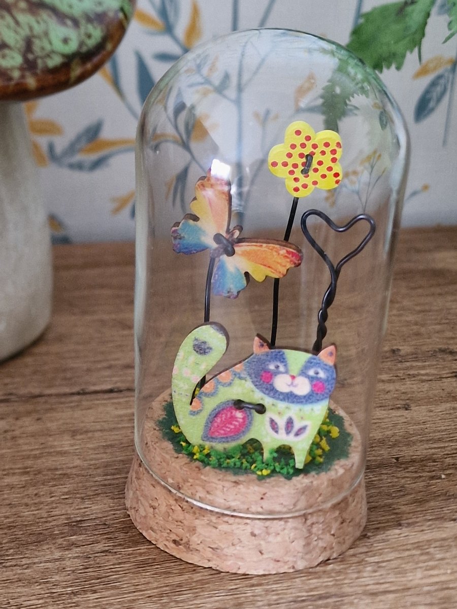 A pretty cat in the garden scene in a glass dome