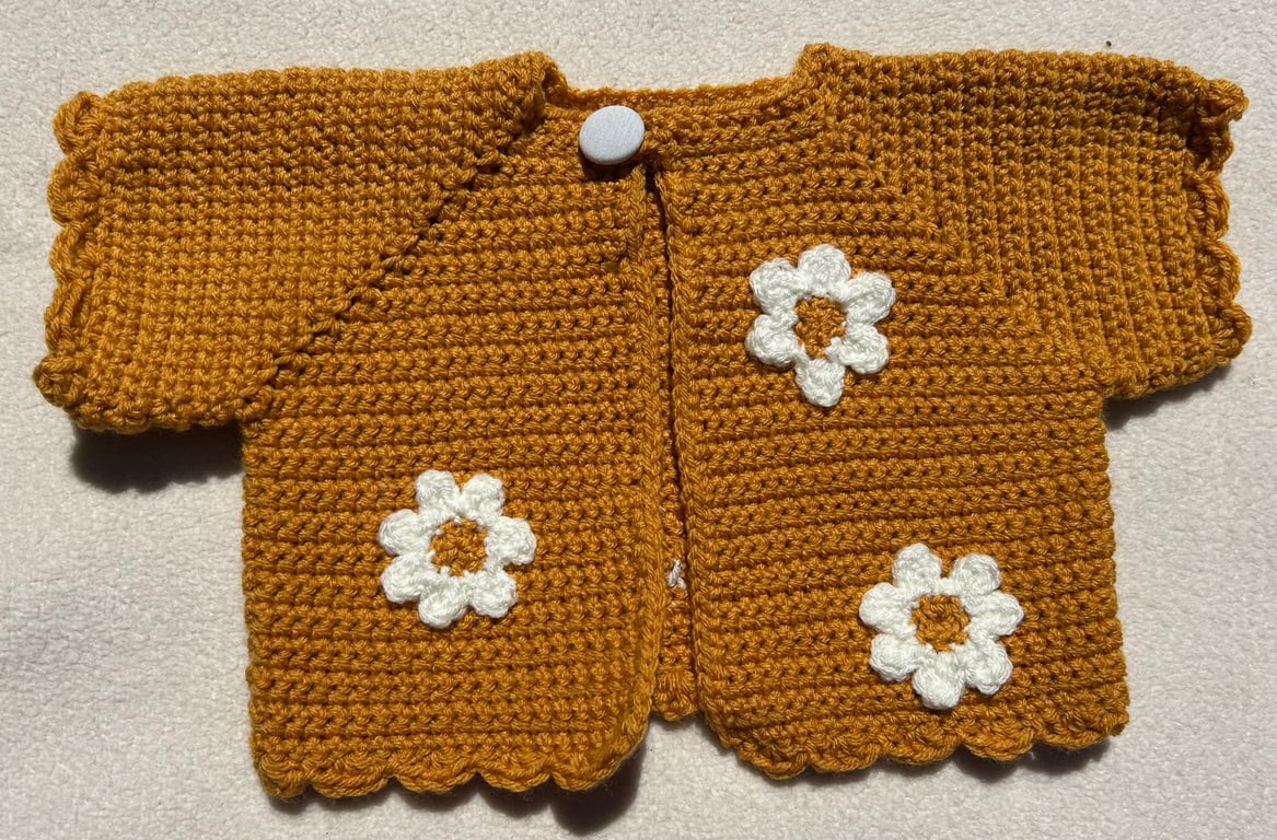 Golden yellow bolero style baby cardigan decorated with daisies.