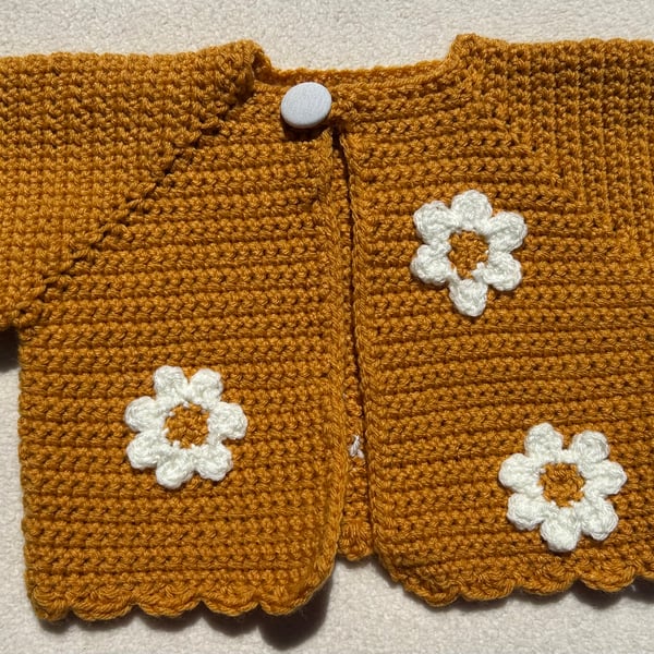 Golden yellow bolero style baby cardigan decorated with daisies.