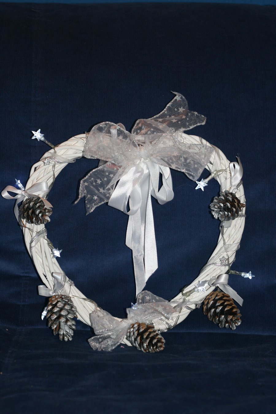 Large white wreath with ribbons, fir cones and white star lights