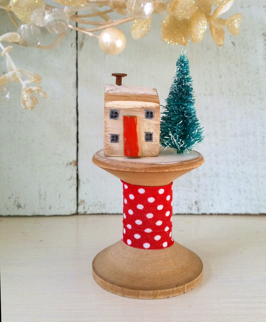 Little wooden Christmas house on a vintage bobbin