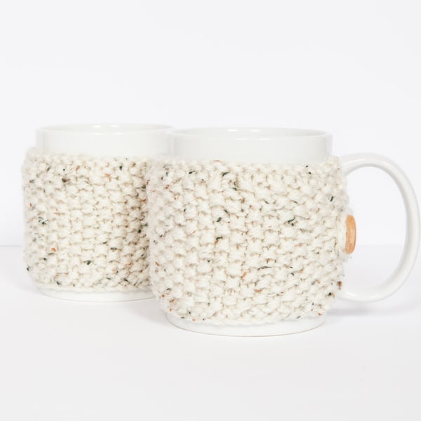 Pair of knitted mug cosies, cup cosy, coffee cosy in oatmeal. Coffee mug cosy