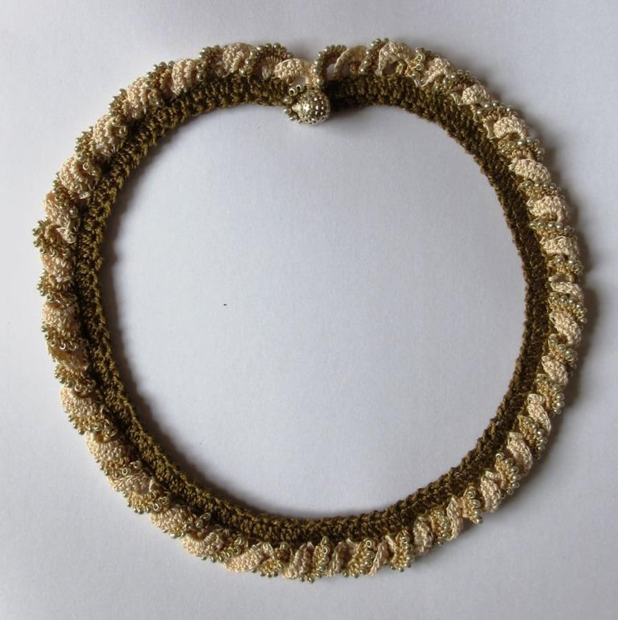 A crocheted necklace in coffee and cream cotton with edging of gold beads