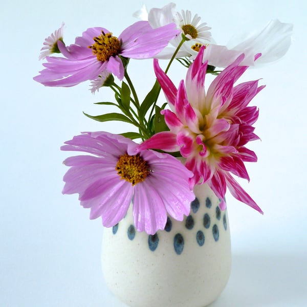 A hand thrown and decorated bud vase .