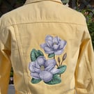 Machine embroidered soft yellow denim jacket with large magnolia design