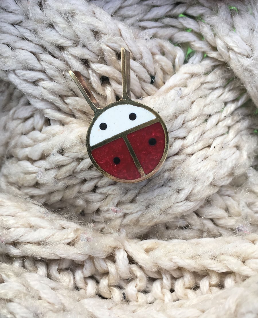 A tiny ladybird pin brooch in resin and metal.