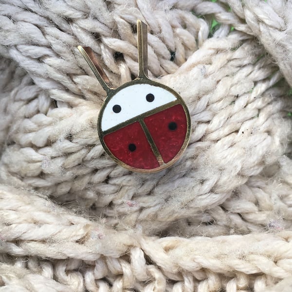 A tiny ladybird pin brooch in resin and metal.