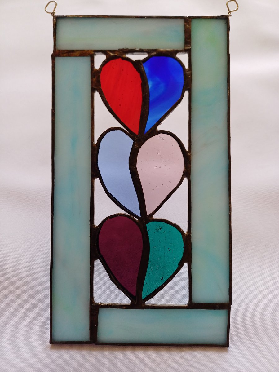 3 stained glass hearts framed with pale blue opaque glass.