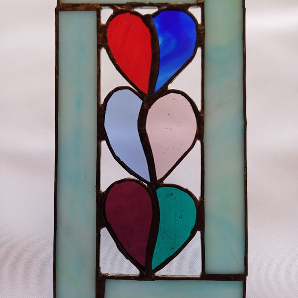 3 stained glass hearts framed with pale blue opaque glass.