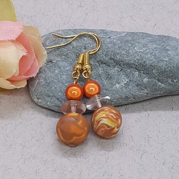 Polymer clay earrings in an orange, yellow, sienna and cream unique swirl design