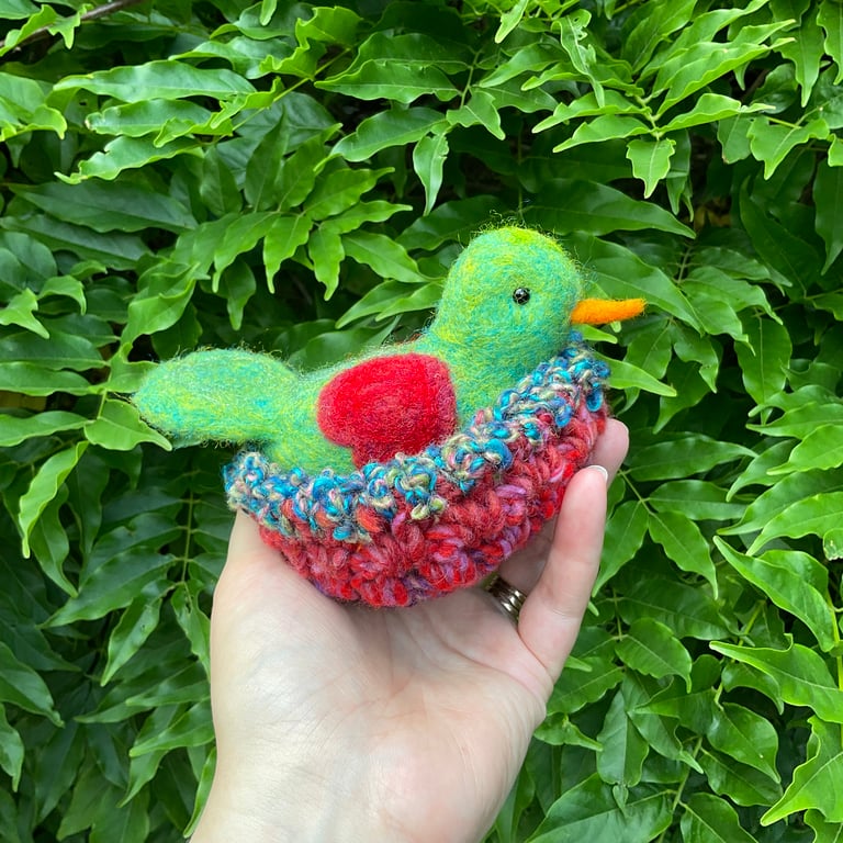 Sweet bird in a beautiful nest with red heart wings