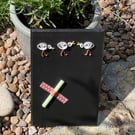 A handmade chalkboard with 3 pesky quilled seagulls at the top of the board