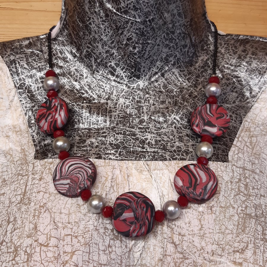 Image of Disc shaped necklace in a red, black and silver swirl design