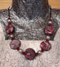 Disc shaped necklace in a red, black and silver swirl design - Image 1