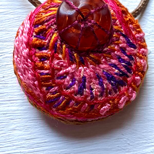 Hand embroidered pendant in warm pinks