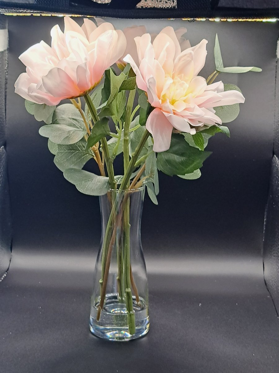 Faux pink dahlias and eucalyptus leaves in glass vase 