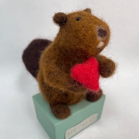 Handcrafted needle felted beaver holding a heart on a wooden box