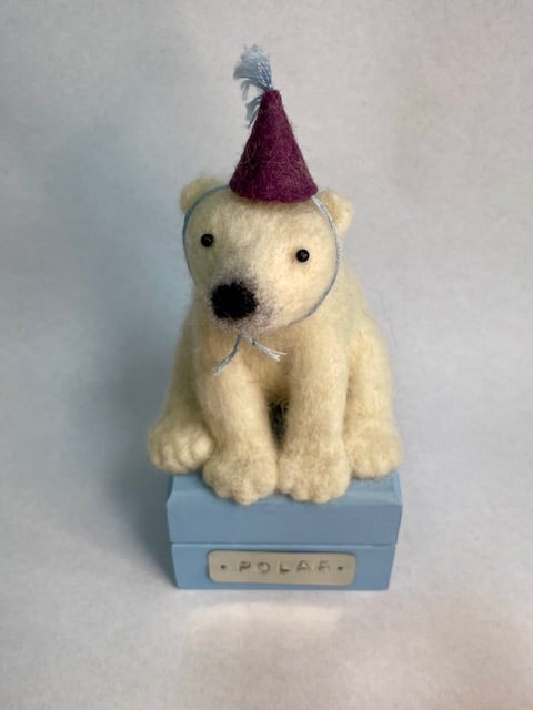 Handcrafted needle felted polar bear with removable party hat on a wooden box