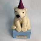 Handcrafted needle felted polar bear with removable party hat on a wooden box
