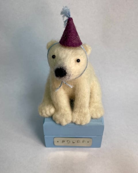 Handcrafted needle felted polar bear with removable party hat on a wooden box