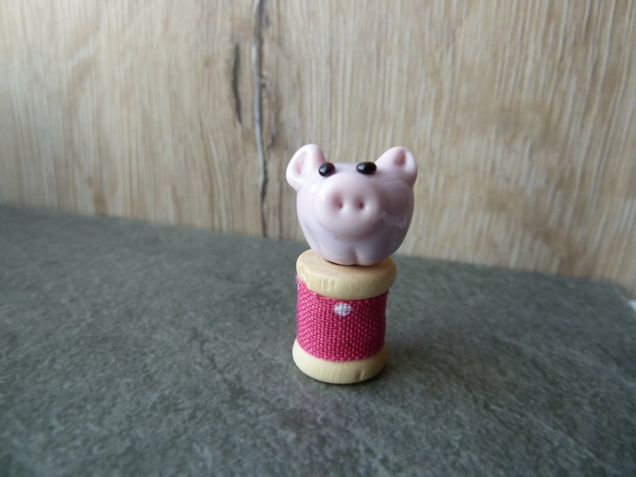 glass pig on wooden spool