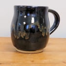 Large pottery mug finished in a black glaze with gold blue tones, handmade