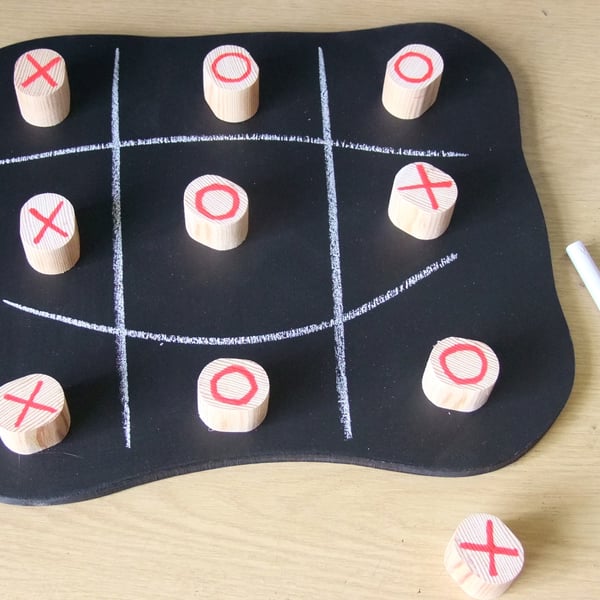 Noughts & Crosses game on a wooden chalk board with large wooden pieces.
