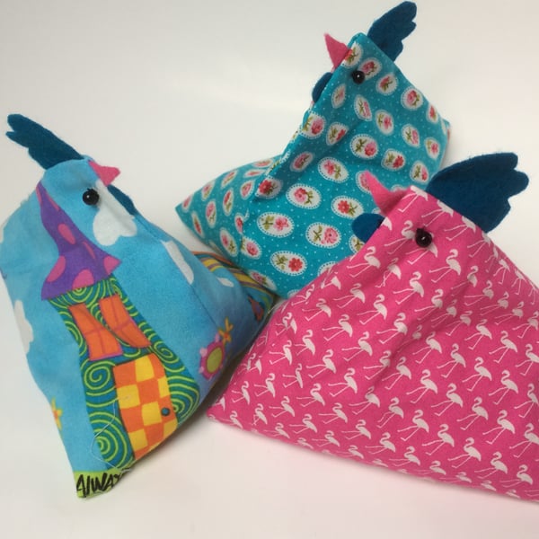 Paper weights. Three chicken bean bag weights in pink and turquoise.