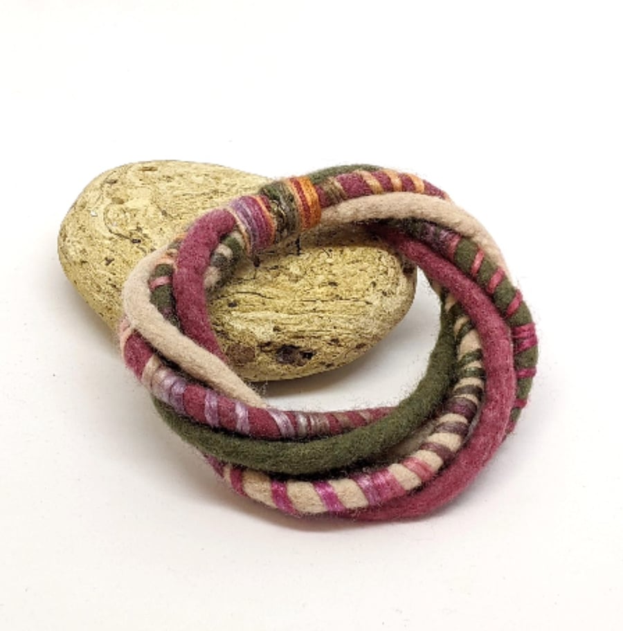 Felted merino cord bracelet in shades of green, cream and mulberry.