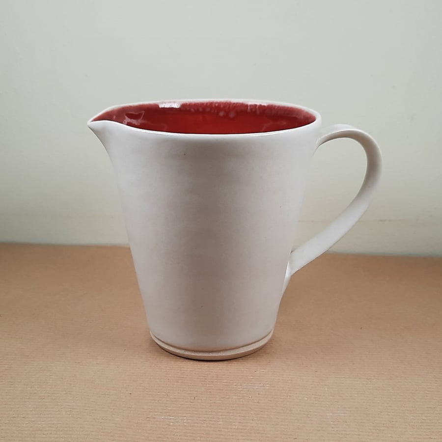 Small red and white hand made ceramic cream jug
