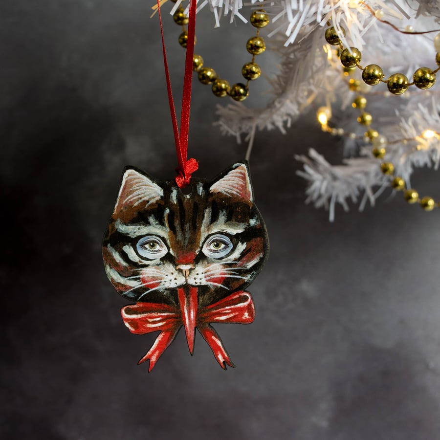 Black tabby cat pulling tongues wooden hanging decoration. Krampus kitty