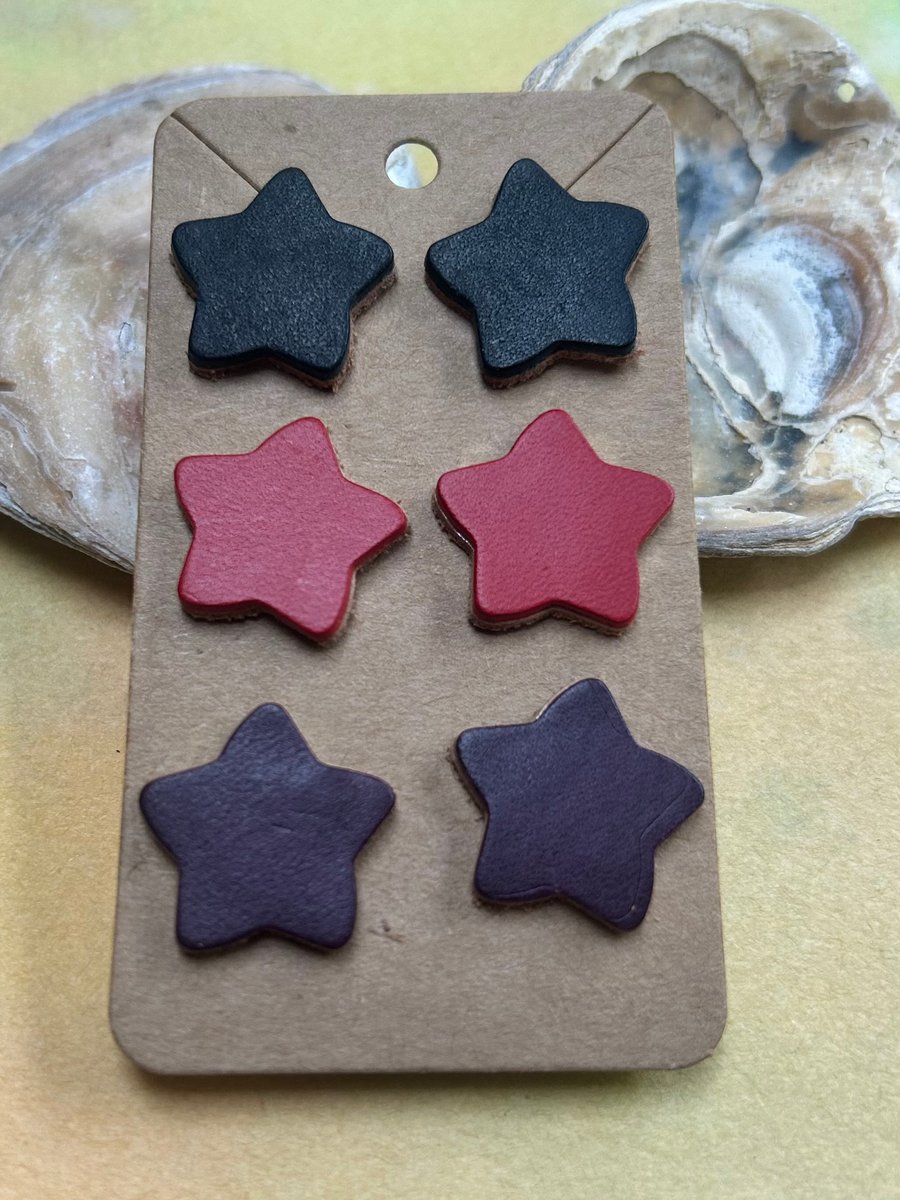 Three pairs of leather star earrings in black red and purple 