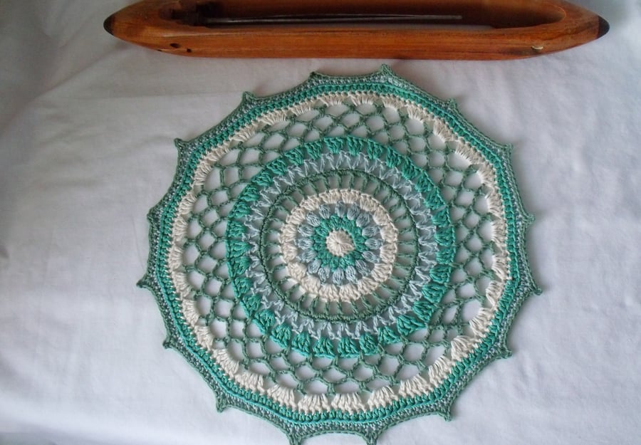 crocheted cotton doily in muted greens and cream, 13 inches diameter