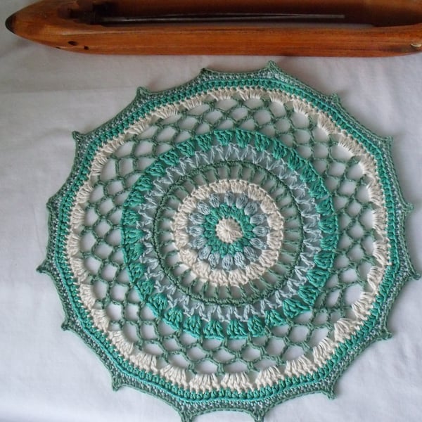 crocheted cotton doily in muted greens and cream, 13 inches diameter