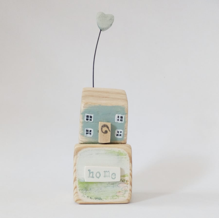 Little wooden house with clay heart on a vintage toy block 'home'