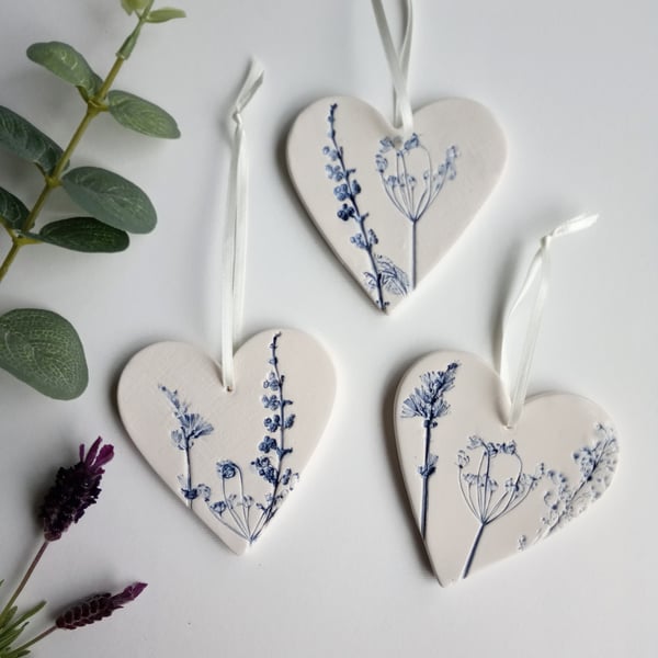 Set of 3 ceramic heart hangings with a botanical print.