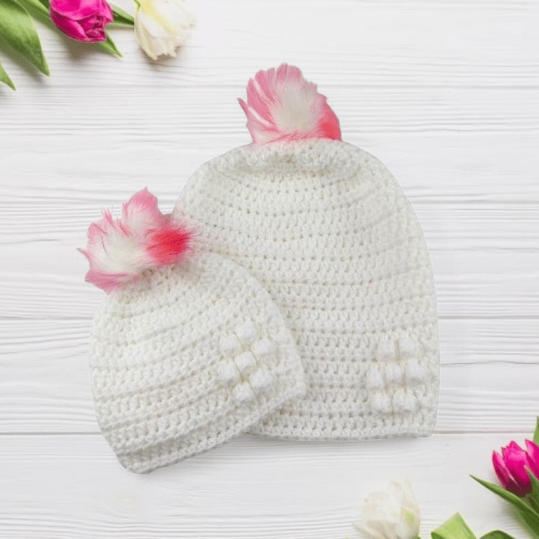 Matching ladies and baby white crocheted hats with detachable faux fur pompoms 