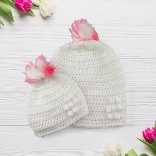 Matching ladies and baby white crocheted hats with detachable faux fur pompoms 